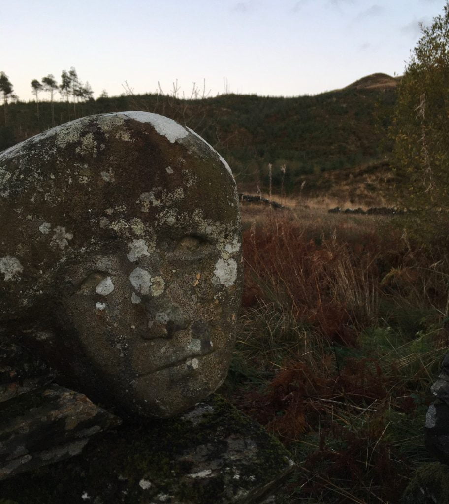 carved stone face in front of hills