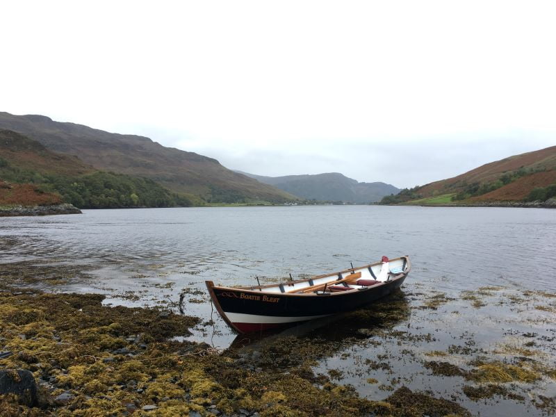 rowing boat at the edge of sea with mountains behind
