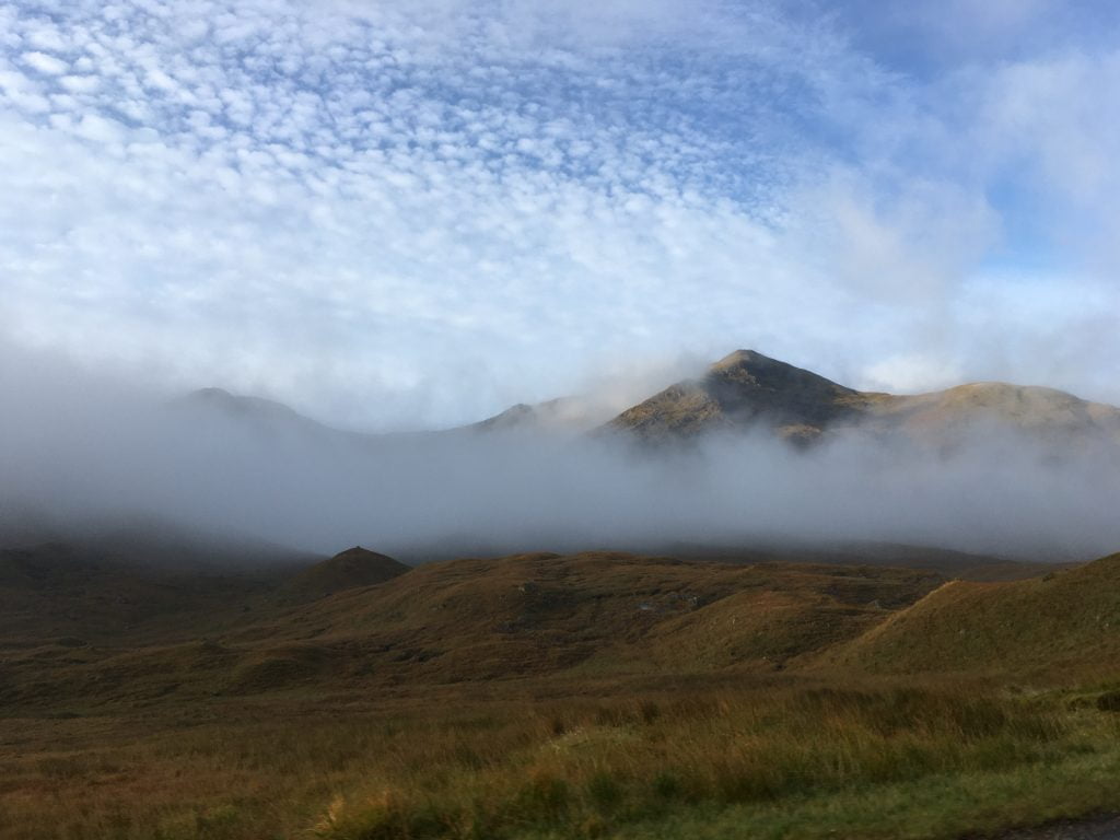 cloud in valley below mountain and blue sky